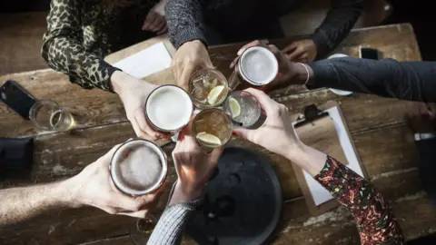 Henrik Sorensen/Getty Aerial shot of a group of people chinking glasses in a pub