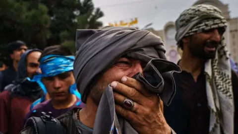 LA Times via Getty Images Afghans outside Kabul airport on 17 August 2021