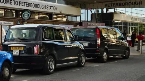 Shariqua Ahmed Row of black cabs parked outside the Peterborough train station 