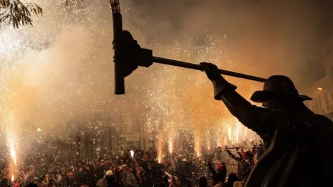 Bridgwater Guy Fawkes Carnival Squibbers lighting their fireworks along Bridgwater High Street in one long row