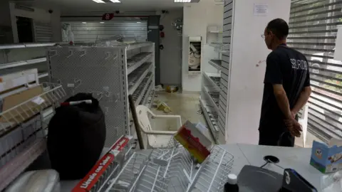AFP A security guard inside a looted pharmacy in Maracay