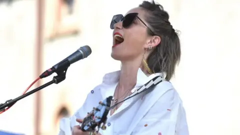 Getty Images KT Tunstall singing during a performance. She is wearing shades.