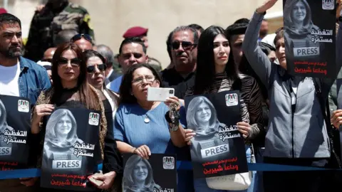 EPA People hold up pictures of Shireen Abu Aqla during a memorial ceremony outside the Palestinian Authority's headquarters in Ramallah, in the occupied West Bank (12 May 2022)