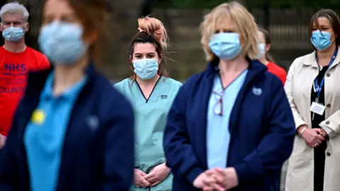 Getty Images Health workers stand outside the Glasgow Royal Infirmary and observe a minute's silence