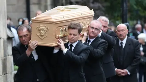 PA Media Declan Donnelly carrying the coffin of his brother, Father Dermott Donnelly into St Mary's Cathedral in Newcastle