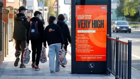 Reuters People next to a sign about coronavirus restrictions in Liverpool