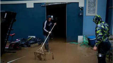 Getty Images Puerto Ricans remove mud from their flooded home