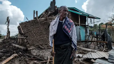 Getty Images A man stands in front of his destroyed house in the village of Bisober in Ethiopia's Tigray region, on December 9, 2020.