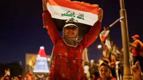 Reuters A young supporter of Shia cleric Moqtada al-Sadr holds up an Iraqi flag at a rally in Baghdad held after the initial results of Iraq's election were announced (11 October 2021)