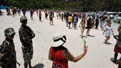 Getty Images Thai park rangers keeping watch as tourists walk along the Maya Bay beach, Thailand, 9 April 2018