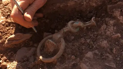 Mike Smith Photo of a bridle bit being unearthed