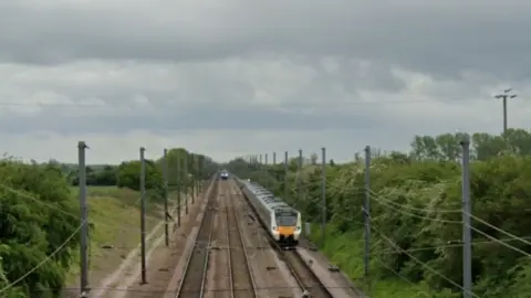 Google Three-line stretch of mainline railway with two trains visible