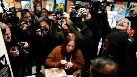 PA Media Reporters and photographers gathering round the first customers buying Spare at WH Smith in Victoria Station