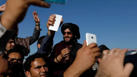 Reuters Afghans take pictures with a militant in Kabul