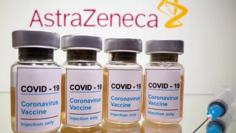 Reuters Vials with a sticker reading, "COVID-19 / Coronavirus vaccine / Injection only" and a medical syringe are seen in front of a displayed AstraZeneca logo in this illustration taken October 31, 2020.