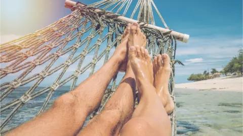 Getty Images A couple lie in a hammock on an Indinesian beach