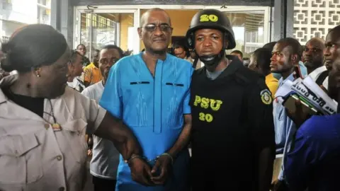 AFP/Getty Images Charles Sirleaf (centre) is escorted outside from a court in Monrovia, Liberia. Photo: 4 March 2019