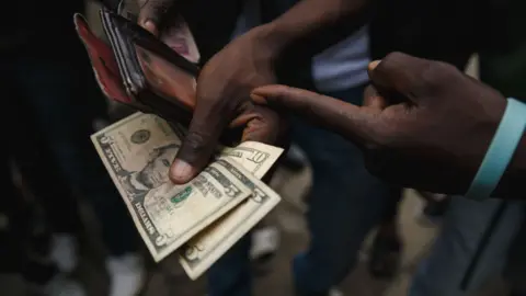 AFP A person holding US dollars in Zimbabwe