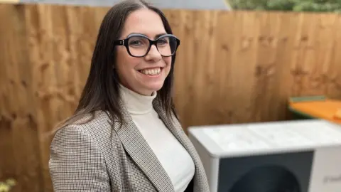 BBC Dr Jenifer Baxter, NICW deputy chairwoman, stood in front of an air source heat pump