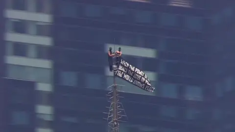 A man and a woman are seen at the top of the Empire State Building.