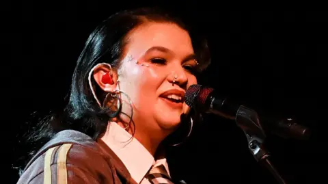 Lola young on stage singing into a microphone