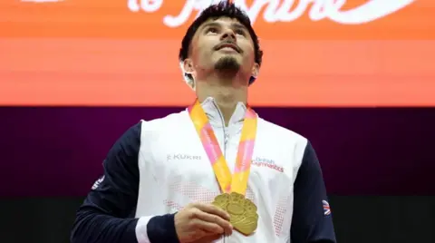 Reuters Jake, a man wearing a white zipped jacket, wearing a gold medal around his neck.