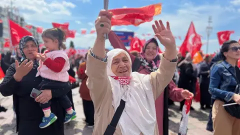 Wietske Burema/ BBC News Two women in headscarves and a child at the rally in support of President Erdogan