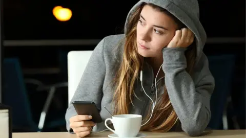 Getty Images Sad girl listening to music on her phone