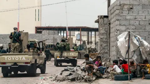 AFP Yemeni fighters loyal to the government patrol a street in Aden (9 August 2018)