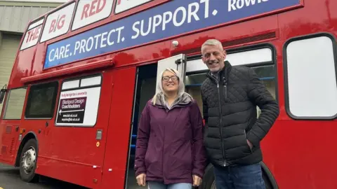 BBC Abbie and Mark Butcher stood next to bus