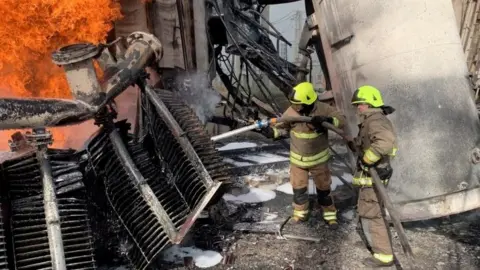 Reuters Firefighters tackle a blaze at an energy facility after a Russian attack in Rivne, western Ukraine. Photo: 22 October 2022