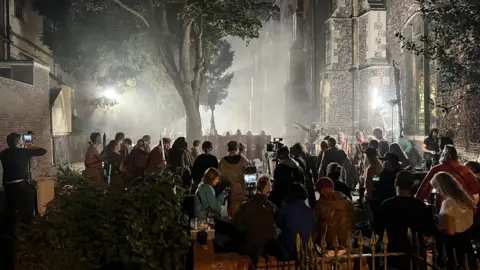 Screen Suffolk St Lawrence's Church in Ipswich flanked by actors with shields and a film crew