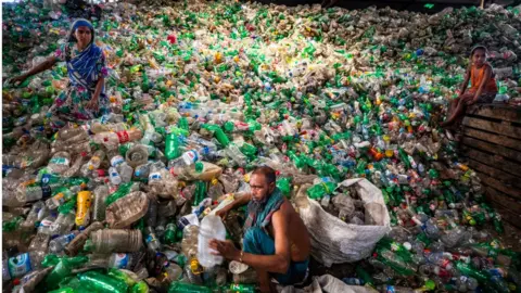 Getty Images Labourers sort through polyethylene terephthalate (PET) bottles in a recycling factory in Dhaka, Bangladesh, on May 5, 2021.