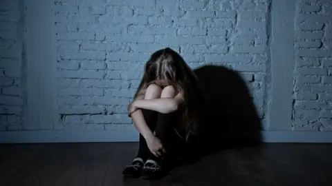 Getty Images Young girl sat on the floor