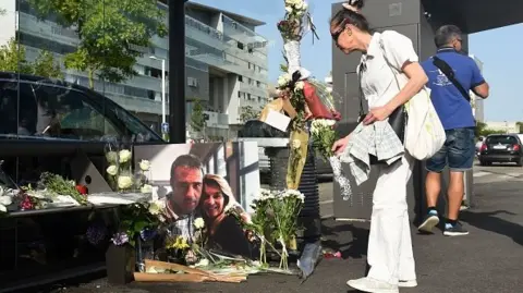 Woman lays flowers next to a picture of the driver killed