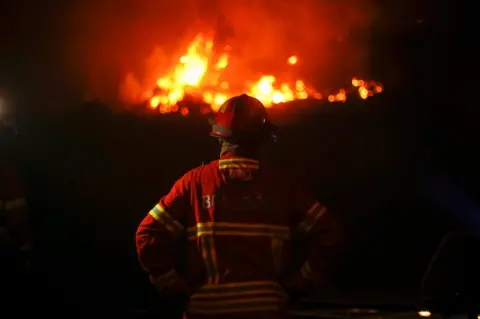 Rafael Marchante / Reuters A firefighter watches an approaching forest fire in Carvalho, near Gois, Portugal