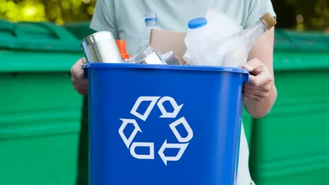 Getty Images Person holding a plastic recycling bin