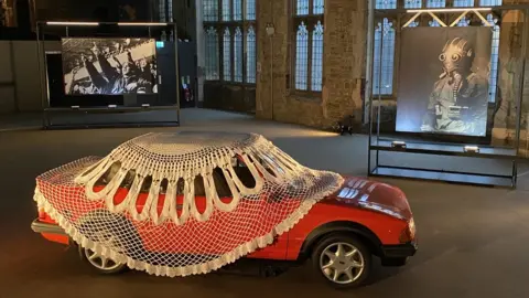 Jasleen Kaur Jasleen Kaur's artwork of a red Ford Mk3 Escort Cabriolet XR3i in the grandiose surroundings of Blackburn’s Cotton Exchange