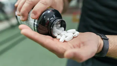 Man spills pills into hand in gym