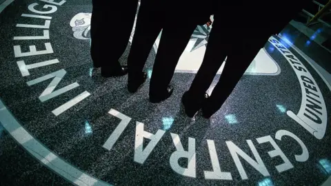 People standing over the CIA symbol at the CIA HQ in Virginia