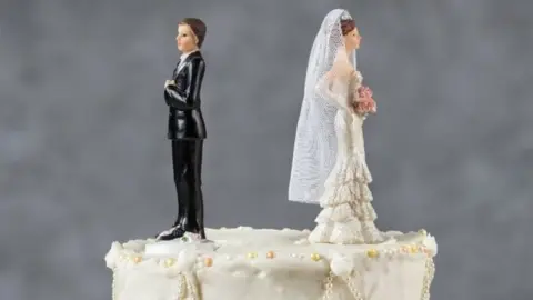 Getty Images Cake toppers facing away from each other on a wedding cake