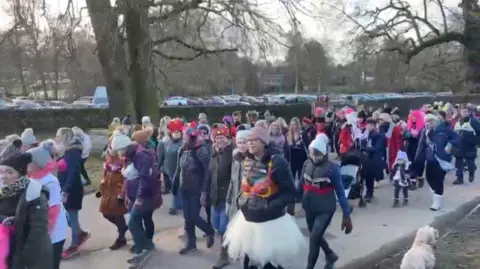 A mass of walkers with bras over their winter wear walking through Bradgate Park