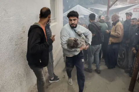 AFP rescue Nuh al-Shagnobi takes an injured child to Al-Ahli Baptist Hospital in Gaza city. 