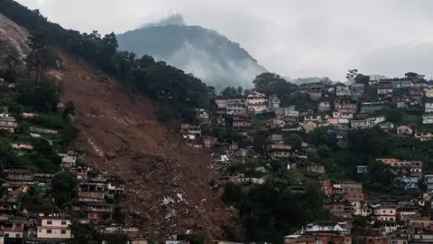 Getty Images An emergency service helicopter flies over a large landslide caused by severe flash floods in Petropolis