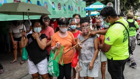 AFP via Getty People queuing for free food in Manila