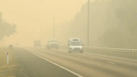 EPA Cars evacuate through thick smoke caused by fires in Victoria