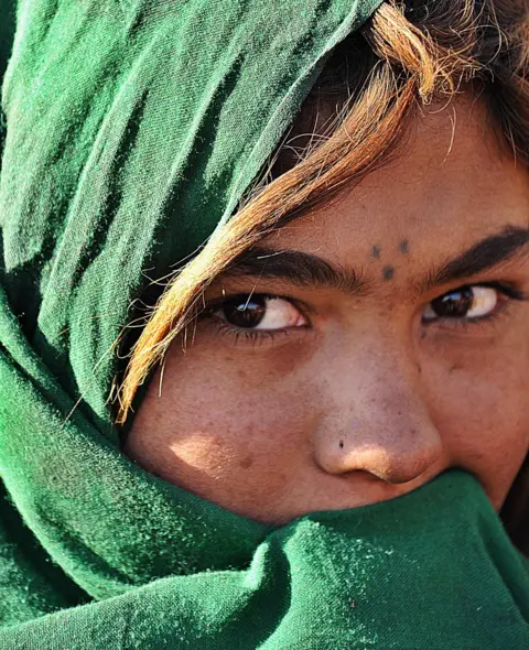 Shah Marai / AFP An Afghan girl from a family which returned from Iran covers her face as she stands in front of her tent on the outskirts of Kabul, February 2008