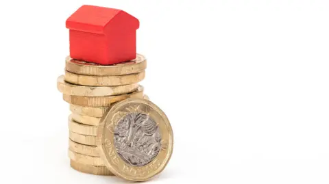 A stack of pound coins with a red house on top