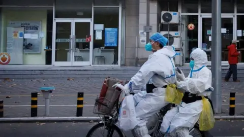 Reuters Pandemic prevention workers on a bike in Beijing