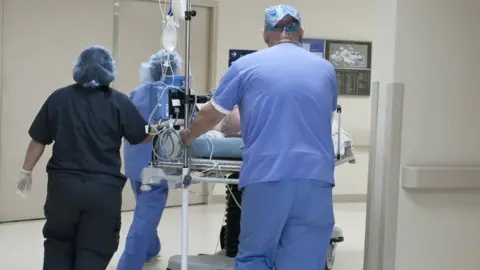 Getty Images Hospital staff with a patient on a trolley